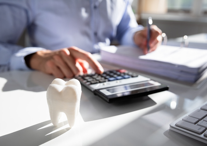 Dr. Peter J. Kim and a masked dental assistant at Pecan Tree Family Dentistry in McKinney, TX, perform a same-day dental procedure on a reclining patient, with digital X-rays displayed on a monitor behind them.